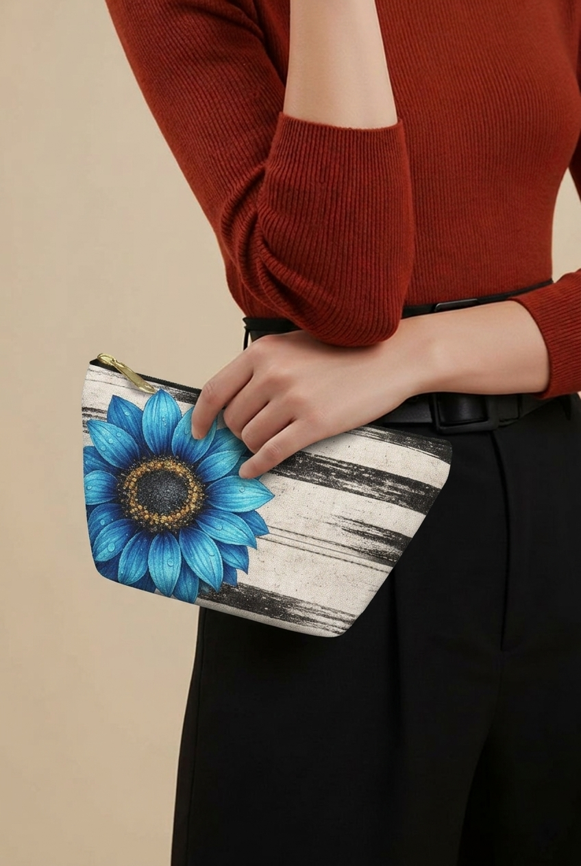 Woman holding the Boho Sunflower Makeup Bag with black-and-beige vintage stripes, large blue sunflower artwork, gold zipper pull, and upright T-bottom shape.